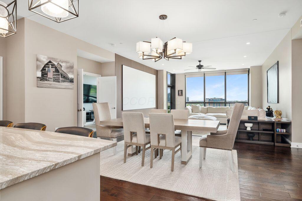 Condominium dining and living area with a stone waterfall island, chandelier and floor-to-ceiling windows overlooking Columbus