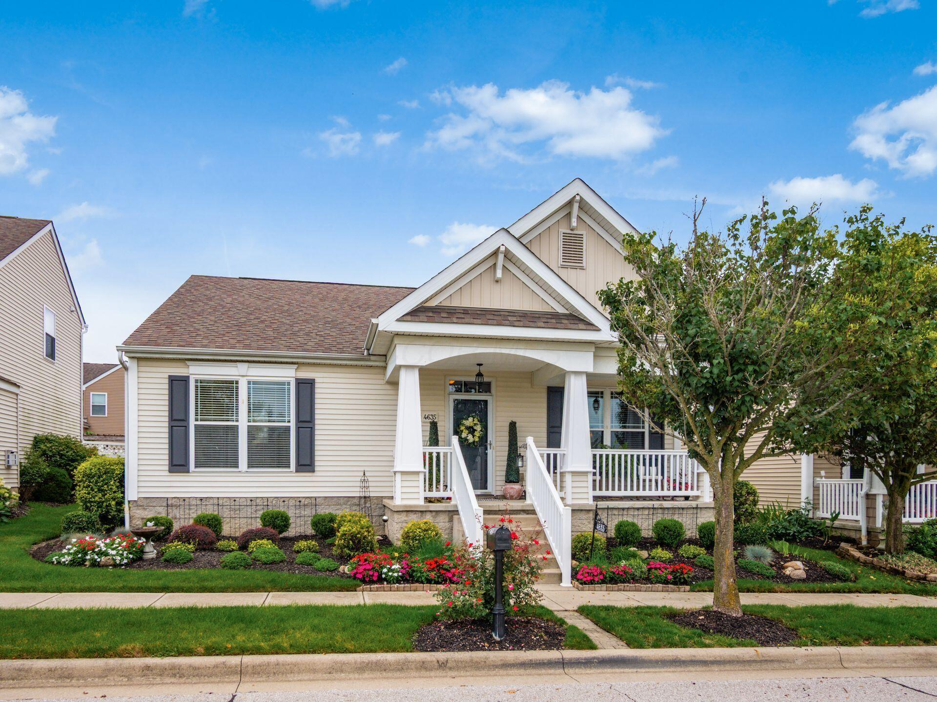 Cream-sided single family home at 4635 Sahalee Drive in Grove City, Ohio, with a gabled front porch, dark shutters and flower beds along the walk
