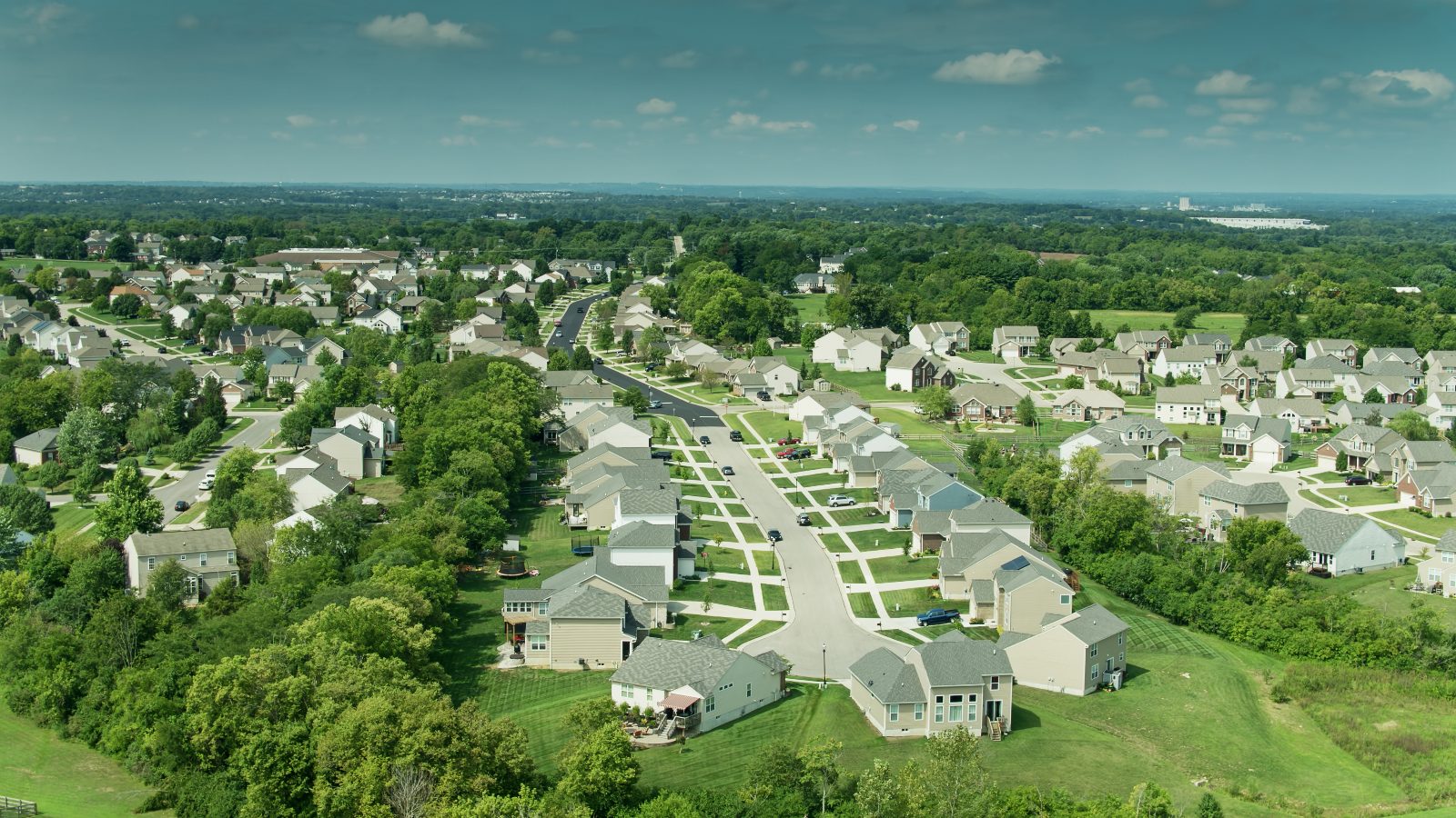 Aerial view of a new-construction neighborhood in Central Ohio, tree-lined streets of newly built homes stretching toward the horizon