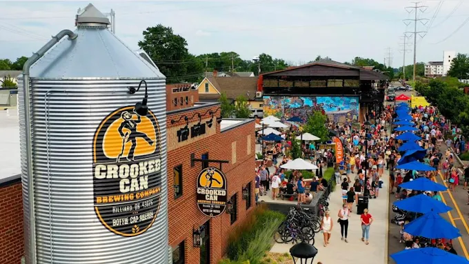 A summer crowd fills the street outside Crooked Can Brewing Company in Hilliard, Ohio, with the grain silo in the foreground and the outdoor stage beyond.